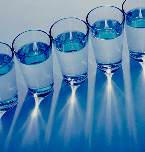 Una foto de vasos de agua en fila diagonal vistos desde arriba.