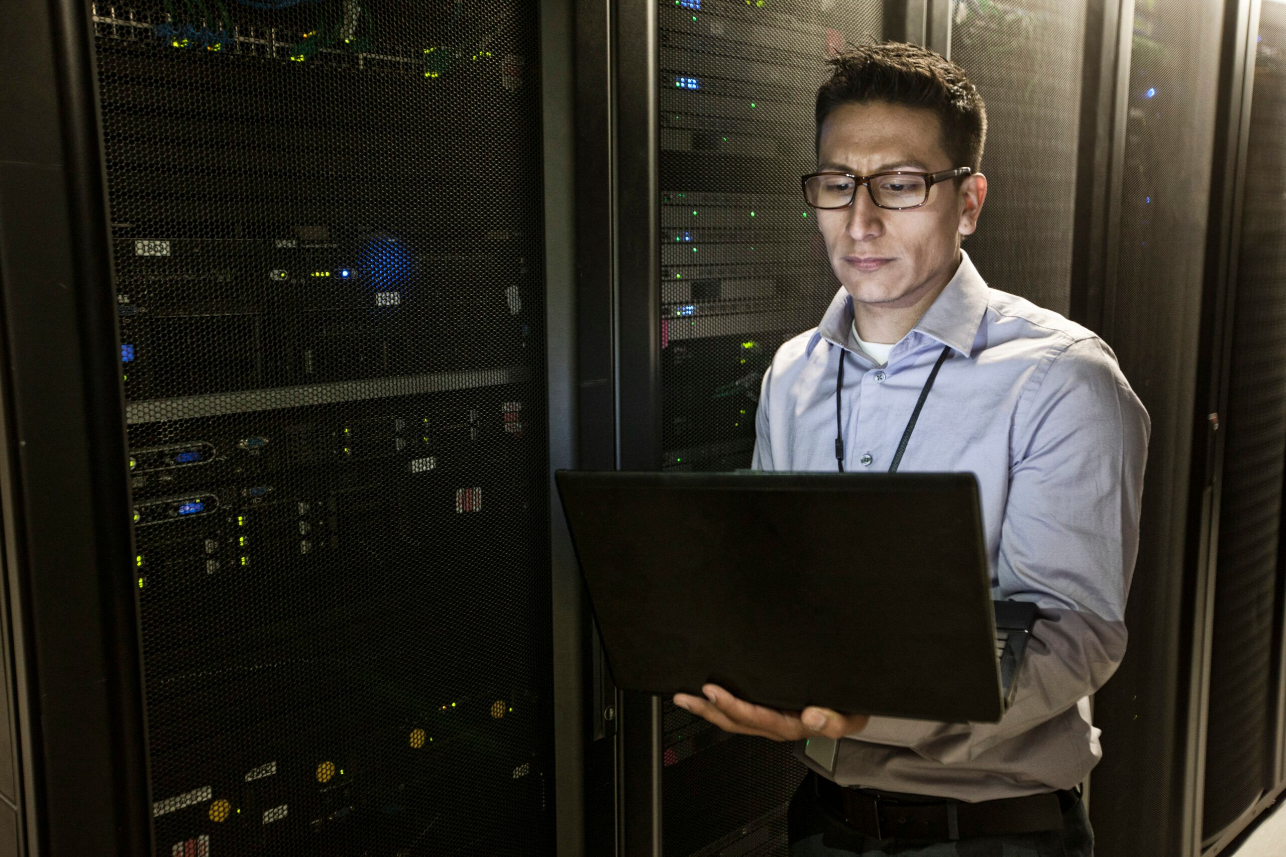 Profesional de TI realizando la gestión de parches de Linux en un centro de datos con racks de servidores y equipos de red