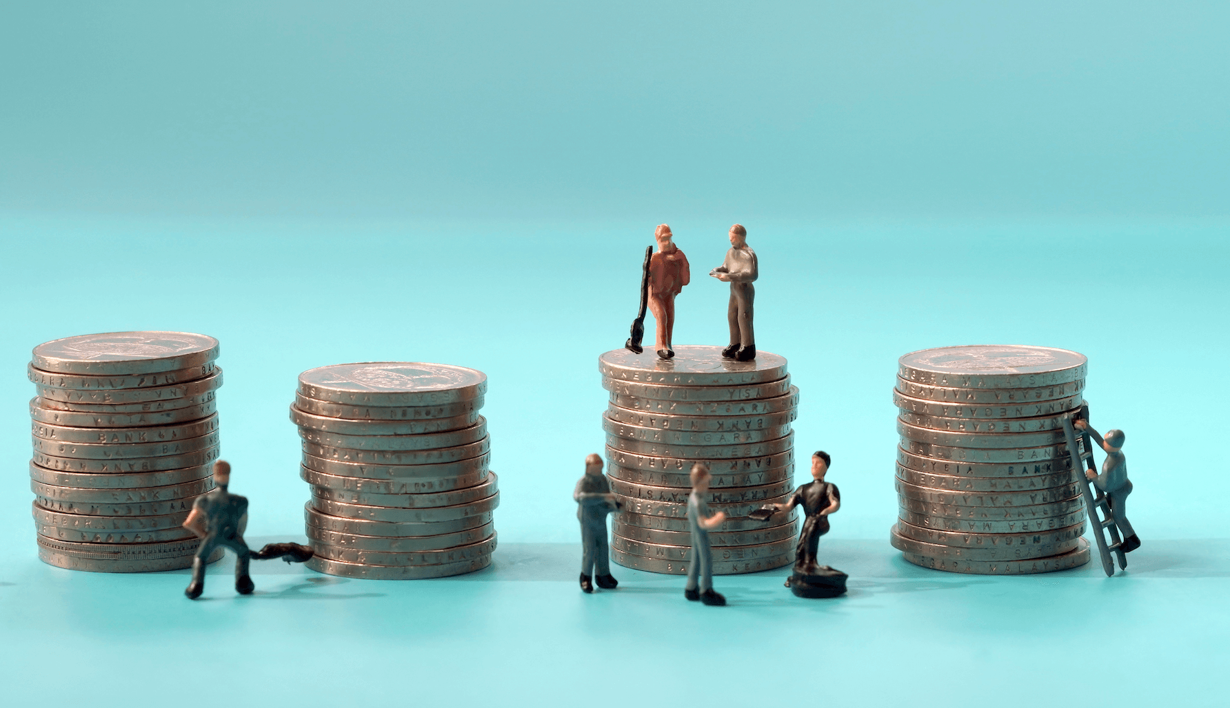 Figuras en miniatura de trabajadores están junto a torres de monedas plateadas.