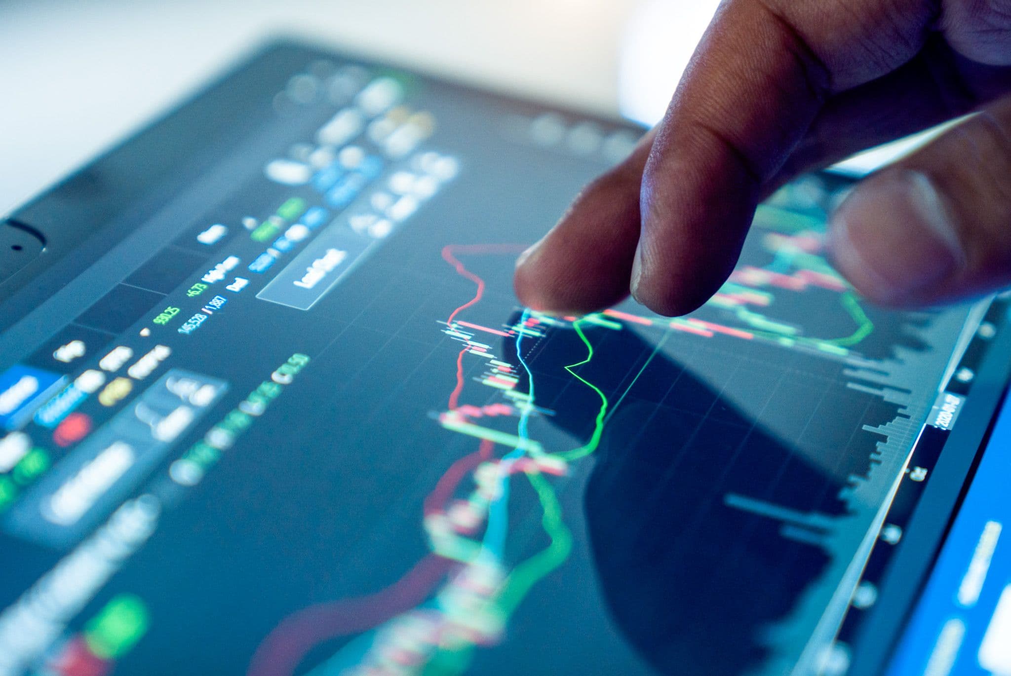 Análisis de mercado: un dedo señala gráficos financieros en una pantalla táctil