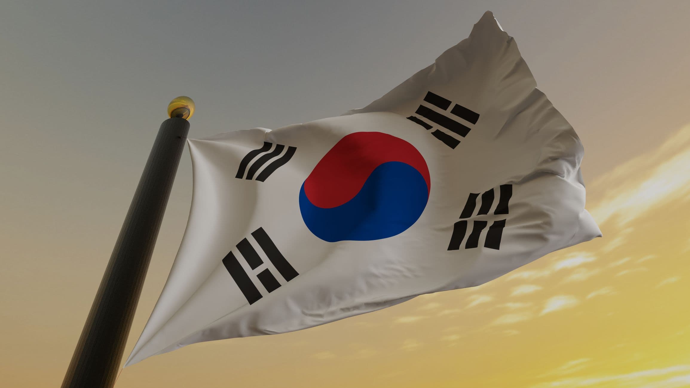 South Korea's flag ripples in the wind. It features a swirling red and blue circle on a white field, surrounded by four trigrams, symbols with three black lines.