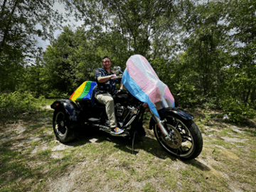 Persona que conduce una motocicleta con una tela colorida que ondea al viento