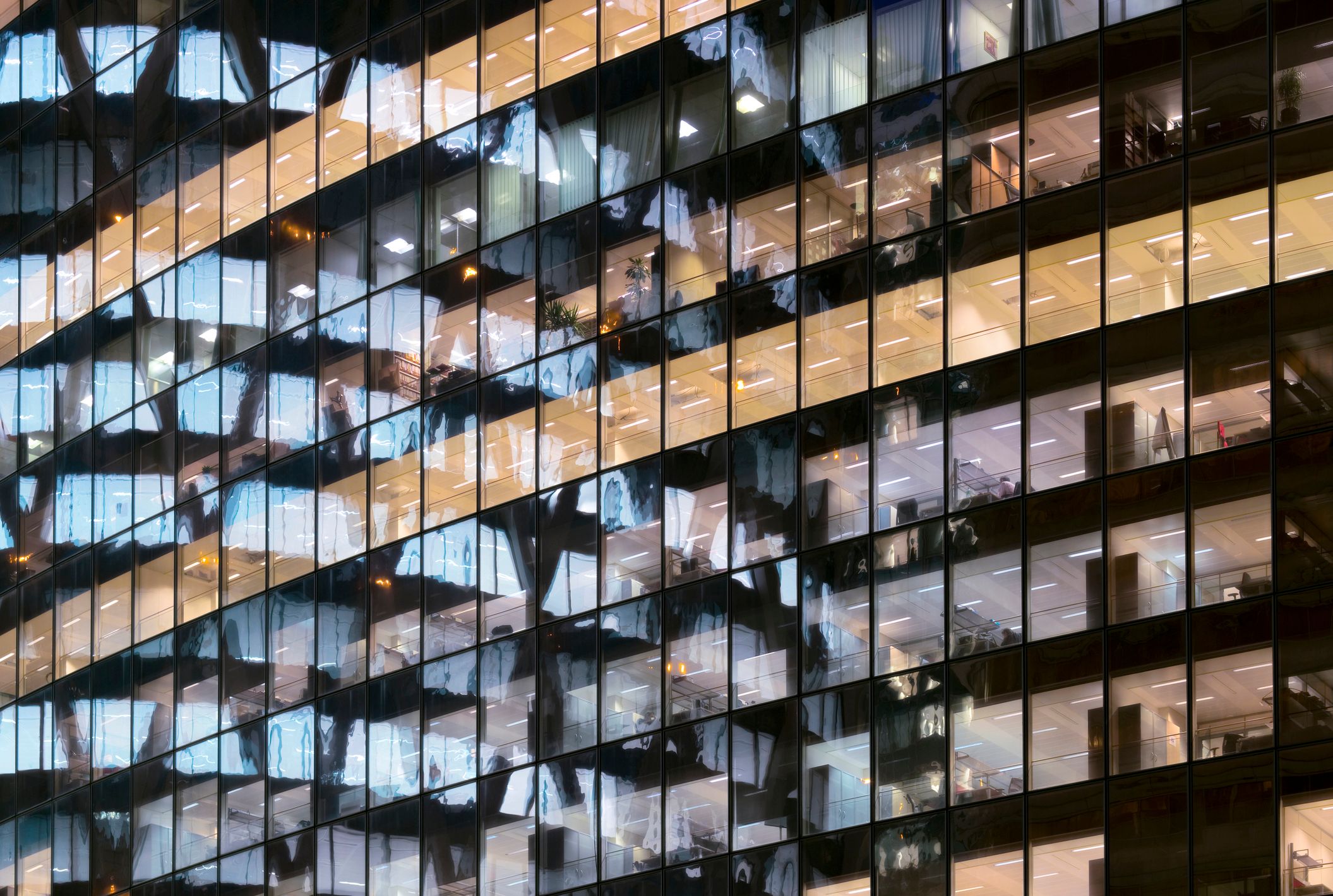 Una foto de torres de oficinas de vidrio, con fila tras fila de ventanas reflejadas en otras ventanas.