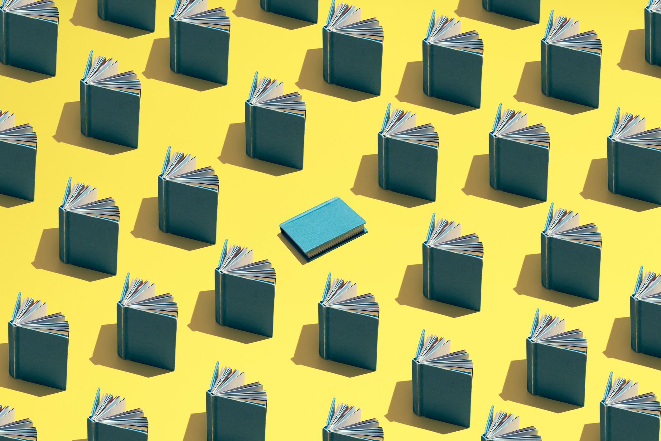 Imagen destacada del blog. Una ilustración de libros apoyados abiertos en filas sobre un campo amarillo y un libro azul en el centro.